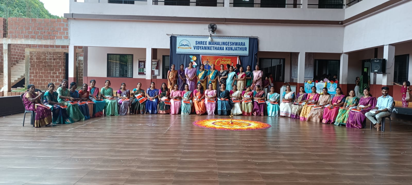 Staff seated around the Onam pookalam